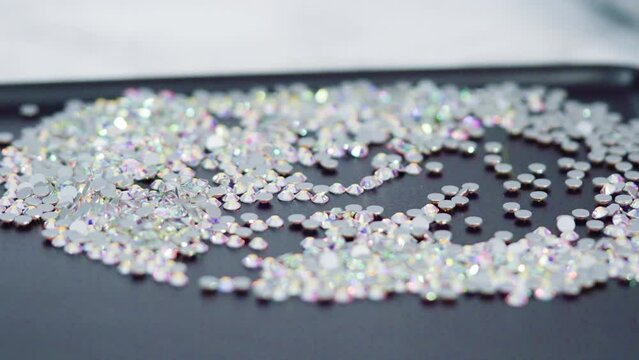 An abundance of white rhinestones with flat back on a black board ready for a craft project.
