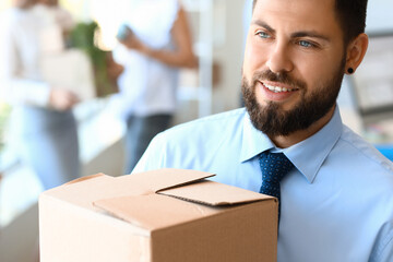 Handsome man holding box with things in office on moving day, closeup