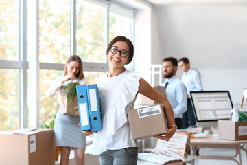 Beautiful businesswoman holding folders and box in office on moving day