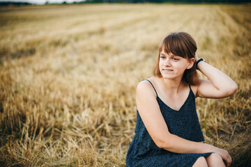 A beautiful girl and a field on which they threshed grain. Woman after harvest. Girl and yellow field
