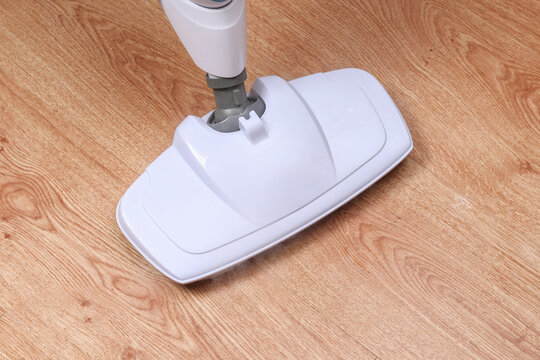 A man washes laminate flooring with a steam mop. Killing germs, clean floor, decontamination.