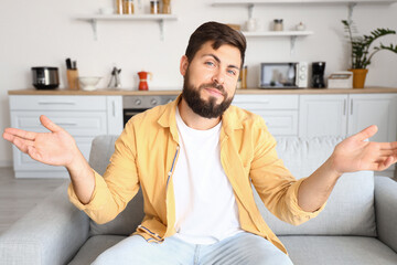 Confused young man video chatting in kitchen