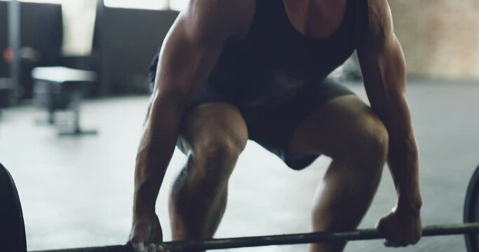 The deadlift. Strong young man lifting a heavy barbell in a gym. Muscular caucasian guy sweating and shouting while pumping iron and weightlifting. Determined bodybuilder exercising in a health club