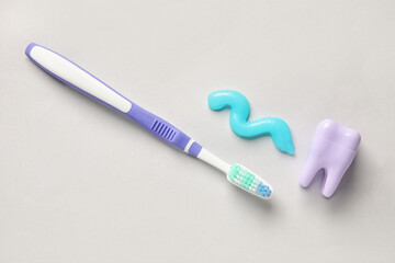 Sample of paste, plastic tooth and brush on light background