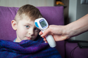 The child's temperature is measured with a thermometer.
