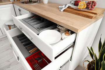Opened drawers with set of kitchen utensils in room