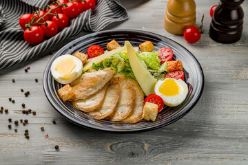 Salad caesar with chicken on plate on grey wooden table