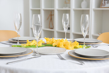 Plates, cutlery, empty glasses and gladiolus flowers on dining table