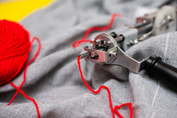 The tufting gun lies on a gray burlap, ready to work with the red yarn in the needle and the...