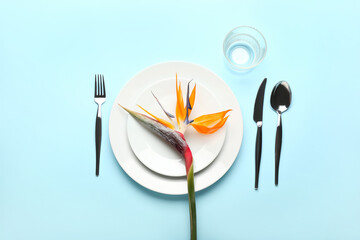 Simple table setting with bird of paradise flower on blue background
