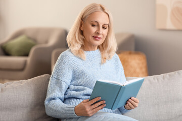 Beautiful mature woman reading book at home