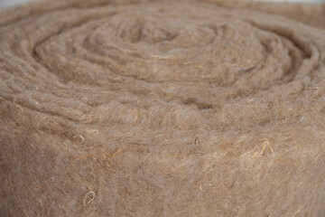 Soft eco-friendly insulating insulation in a roll of hemp and linen close-up, twisted into a roll, thermal insulation, soundproofing,  background