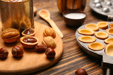 Board of tasty walnut shaped cookies with boiled condensed milk on wooden background, closeup