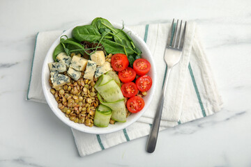 Delicious lentil bowl with blue cheese, tomatoes and cucumber on white marble table, top view