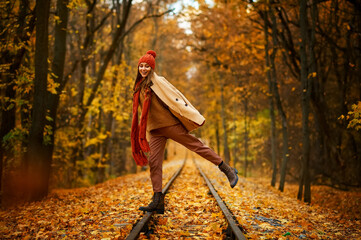 Woman jumping over railroad in autumn forest