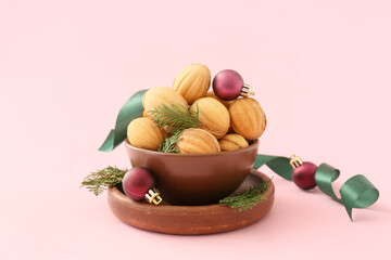 Obraz na płótnie Canvas Bowl of tasty walnut shaped cookies with boiled condensed milk, Christmas decorations and ribbon on color background