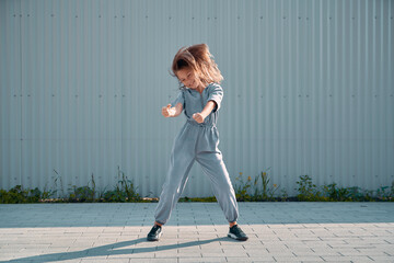 Dancing child girl happy having fun moving with waving hairs on urban background. Energetic joyful...