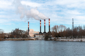 Factory chimneys emit puffs of smoke against the blue sky. The concept of air pollution,...