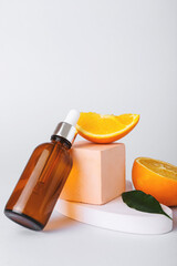 Bottle of essential oil and fresh orange on light background