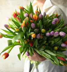 a large multi-colored bouquet of tulips, a girl holds a bouquet of tulips