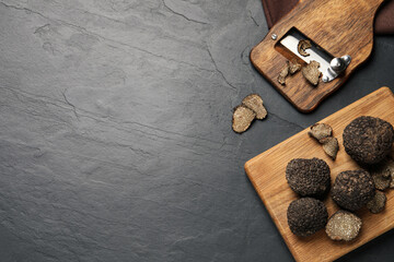 Wooden shaver with whole and sliced truffles on black table, flat lay. Space for text - obrazy, fototapety, plakaty