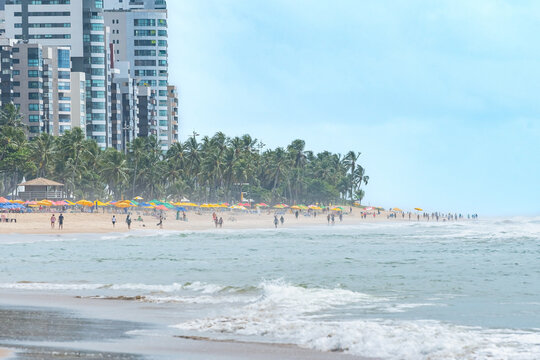 Morning at the beach of Boa Viagem in Recife, Pernambuco state, Brazil. People on the beach, the sand strip, the sea, coconut trees and the city buildings on background.