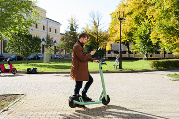 Transportation ecology. Green sustainable mobility Young man unlocks an e-scooter with his mobile phone. Electric scooter new way city. Green transportation. Sustainable climate neutral cities goals.