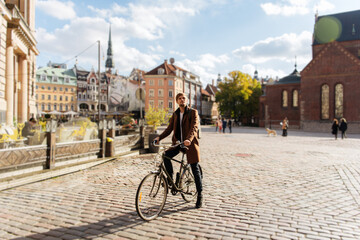 Young man riding a bike. Sustainable mobility transport New way of inclusive cities mobility. Green transportation. Sustainable climate neutral city goals. Green mobility and transportation - obrazy, fototapety, plakaty