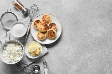 Plate with tasty cottage cheese pancakes and ingredients on grey background