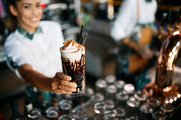 Close-up of female barista serves chocolate mocha with whipped cream.