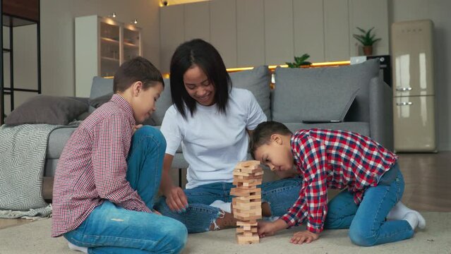 Happy family mother and two sons having fun time and playing jango. Mom lose