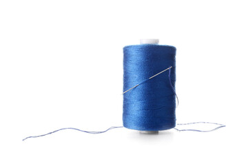 Blue sewing thread spool and needle on white background