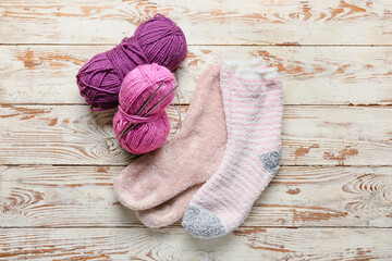 Fototapeta na wymiar Warm socks, knitting yarn and needles on light wooden background
