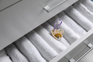 Beautiful heart shaped scented wax sachet in dresser drawer with white towels, closeup