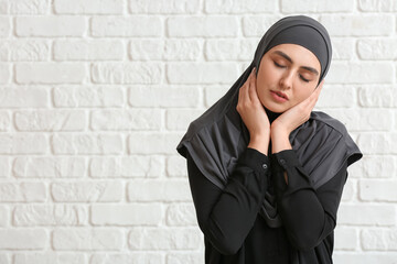 Naklejka premium Beautiful Muslim woman on white brick background
