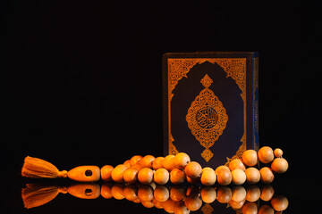 Koran and Muslim prayer beads on dark background
