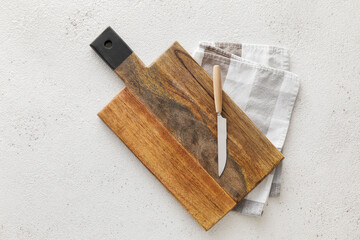 Wooden cutting board, knife and napkin on white background