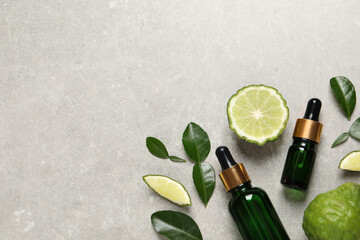 Glass bottles of bergamot essential oil and fresh fruits on light table, flat lay. Space for text - obrazy, fototapety, plakaty