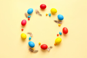 Frame made of multicolored Easter eggs and feathers on light background