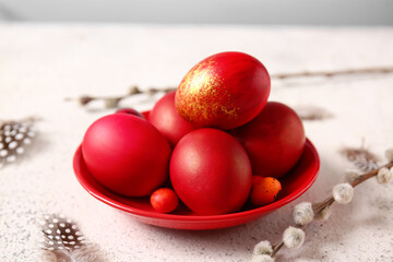 Plate with stylish Easter eggs and willow branches on light background