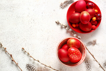 Plate and bowl with stylish Easter eggs, feathers and willow branches on light background