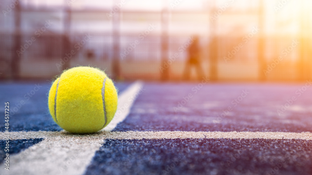 Wall mural yellow ball on floor behind paddle net in blue court outdoors. padel tennis