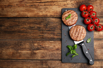 Tasty grilled hamburger patties served on wooden table, flat lay. Space for text