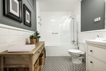 Beautifully decorated bathroom with white tiles on the walls, natural wood furniture and a bathtub with a screen