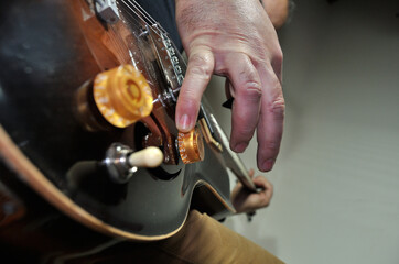 Pessoa do sexo masculino a tocar guitarra tipo jazz com o dedo mindinho a controlar  botão de volume da guitarra