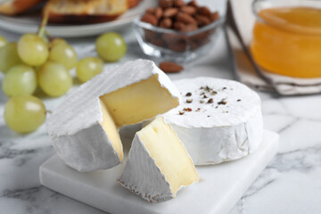 Tasty brie cheese on white marble table