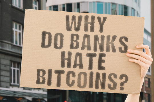 The question " Why do banks hate bitcoins? " on a banner in men's hand with blurred background. Consumer. Crash. Crisis. Cyber. Economic. Law. Problem. Issue. Trade. Wealth. Market. Exchange. Trading