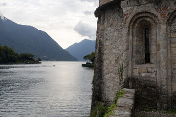 Fototapeta na wymiar Old stone monument next to lake como with a boat and natural landscape in como, italy
