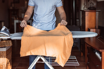 man placing a T-shirt on the ironing board