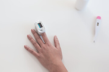 Pulse oximeter on a woman's finger. blood oxygen saturation. The patient measures the saturation of the blood with an electronic pulse oximeter on the finger - 484522473